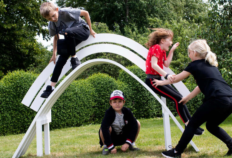 Børn leger på hvid bænk i parken ved Kunstmuseet Brundlund Slot