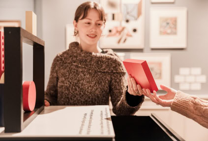 A young woman is holding a squared figure, trying to combine different shapes to create compelling compositions