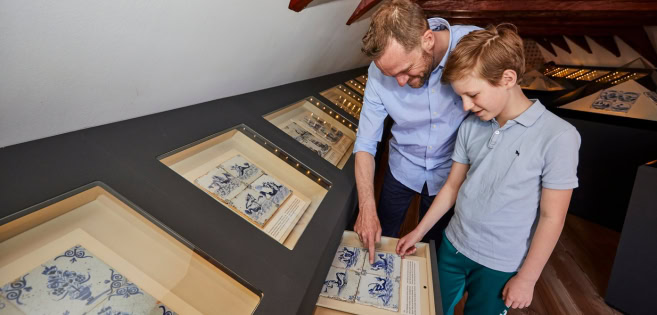 A man and a boy are exploring Dutch tiles at the Cultural History Museum in Tønder