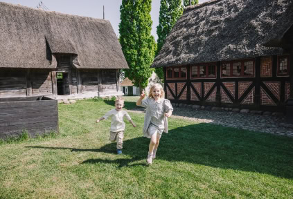 Zwei Kinder laufen im Grünen beim Freilichtmuseum Haderslev
