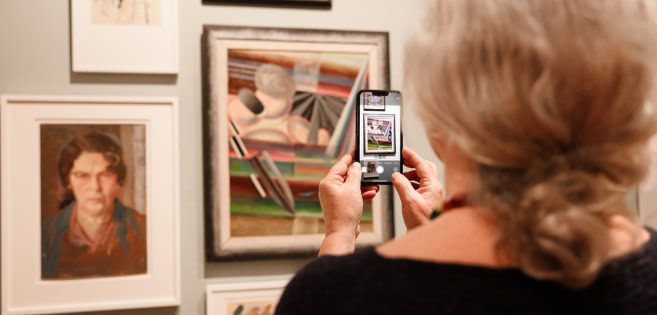 A woman is discovering the artworks of Franciska Clausen at the art exhibition in Brundlund Castle and Art Museum