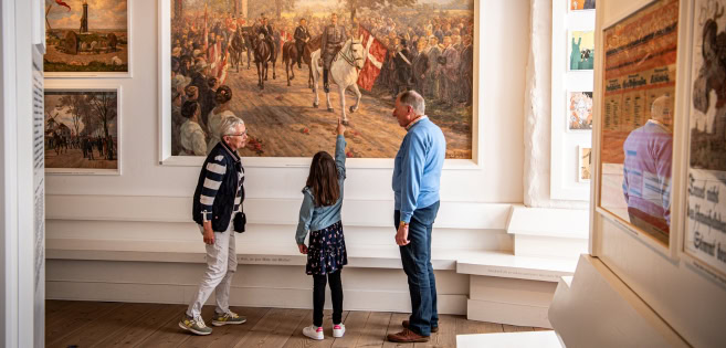 Ein Ehepaar und ein Kind betrachten ein Gemälde im Schloss Sonderburg