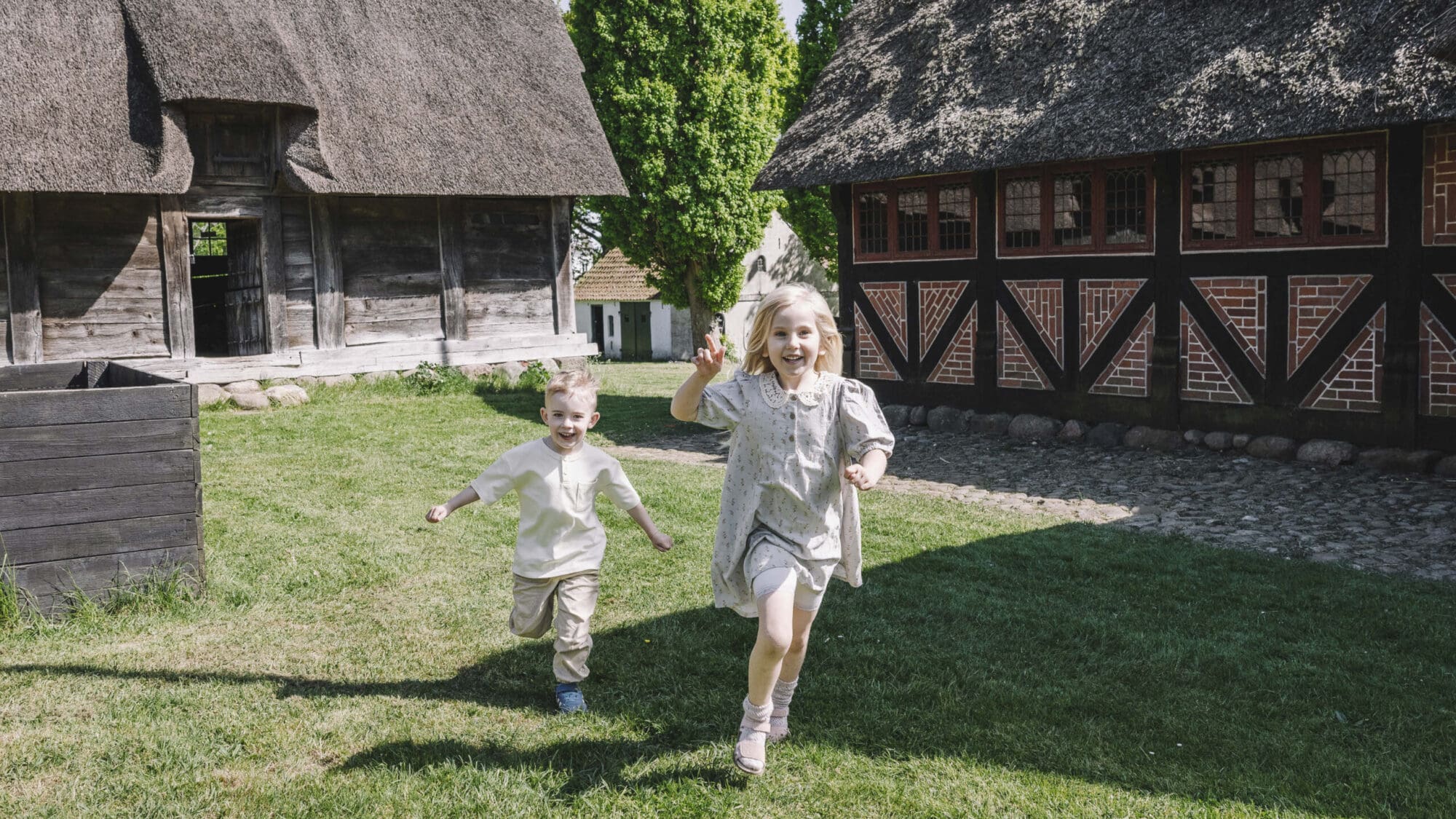 En dreng og en pige løber mellem gamle bindingsværkshuse