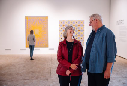 A couple is standing in the exhibition at the Art Museum in Tønder, while another woman is looking at art in the background