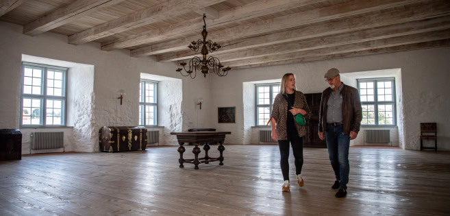 Ein Mann und eine Frau gehen durch einen historischen Raum im Schloss Sonderburg