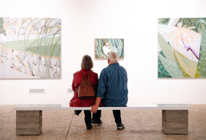 Mand og kvinde sidder på en bæk og ser på kunst på Kunstmuseet i Tønder.